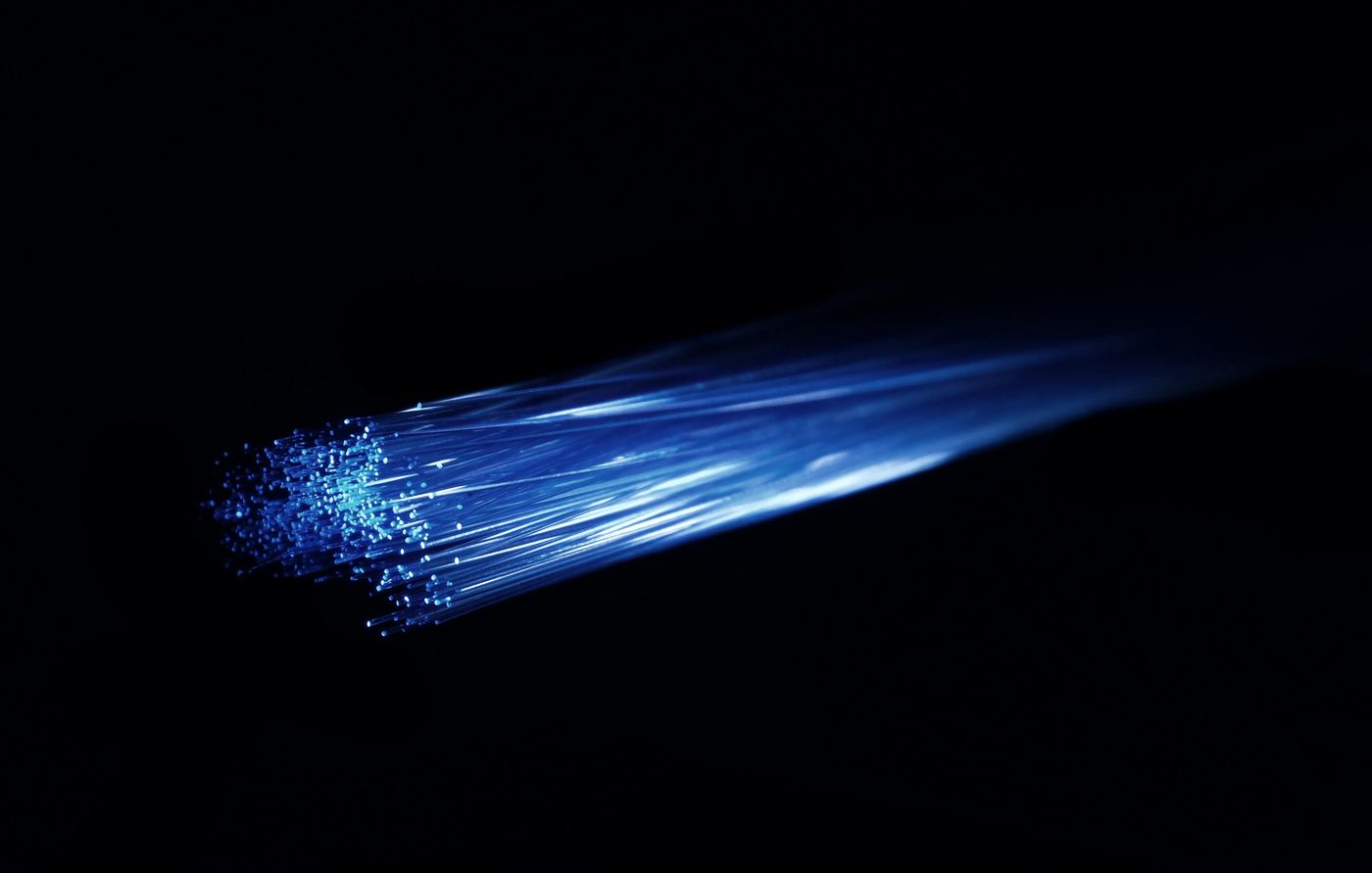A bundle of optical fibres carrying blue light in the dark