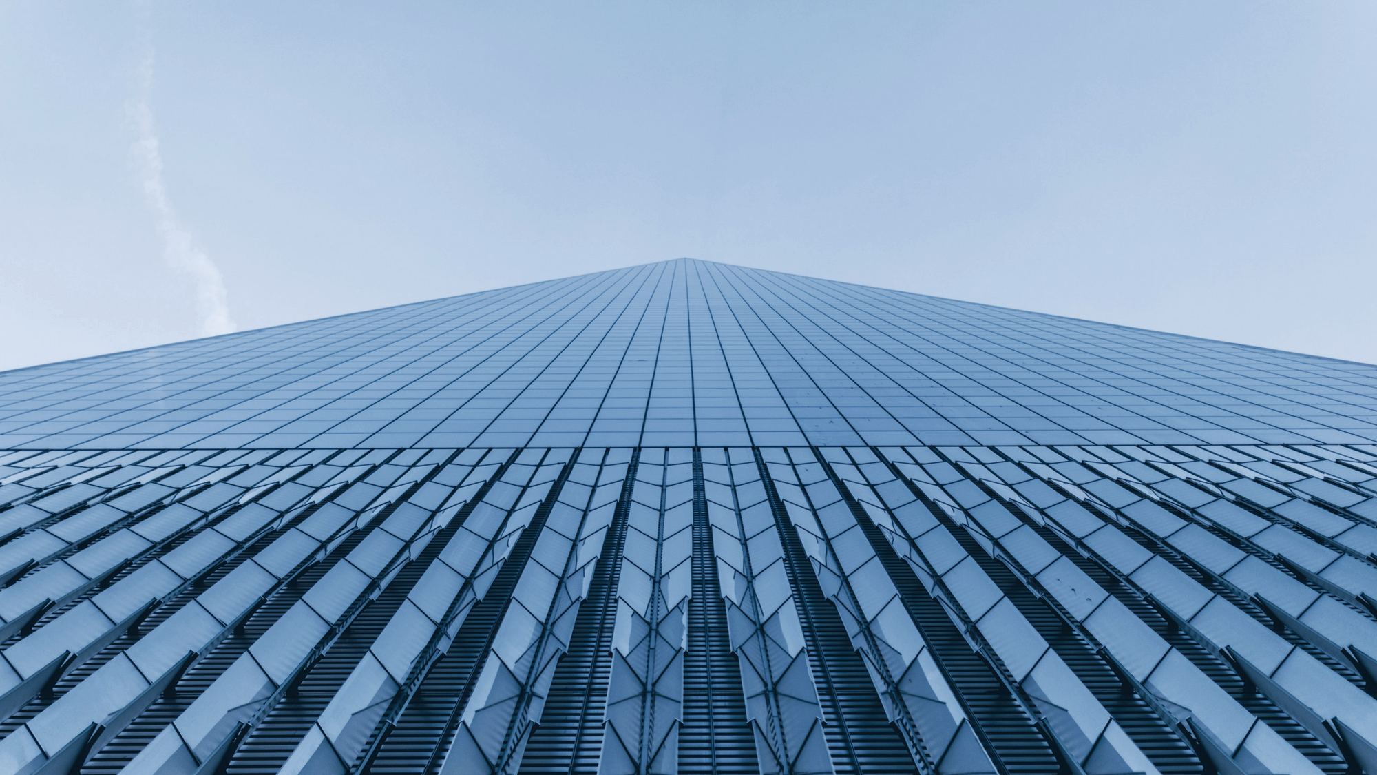 Looking up the glass face of a tower into a blue sky